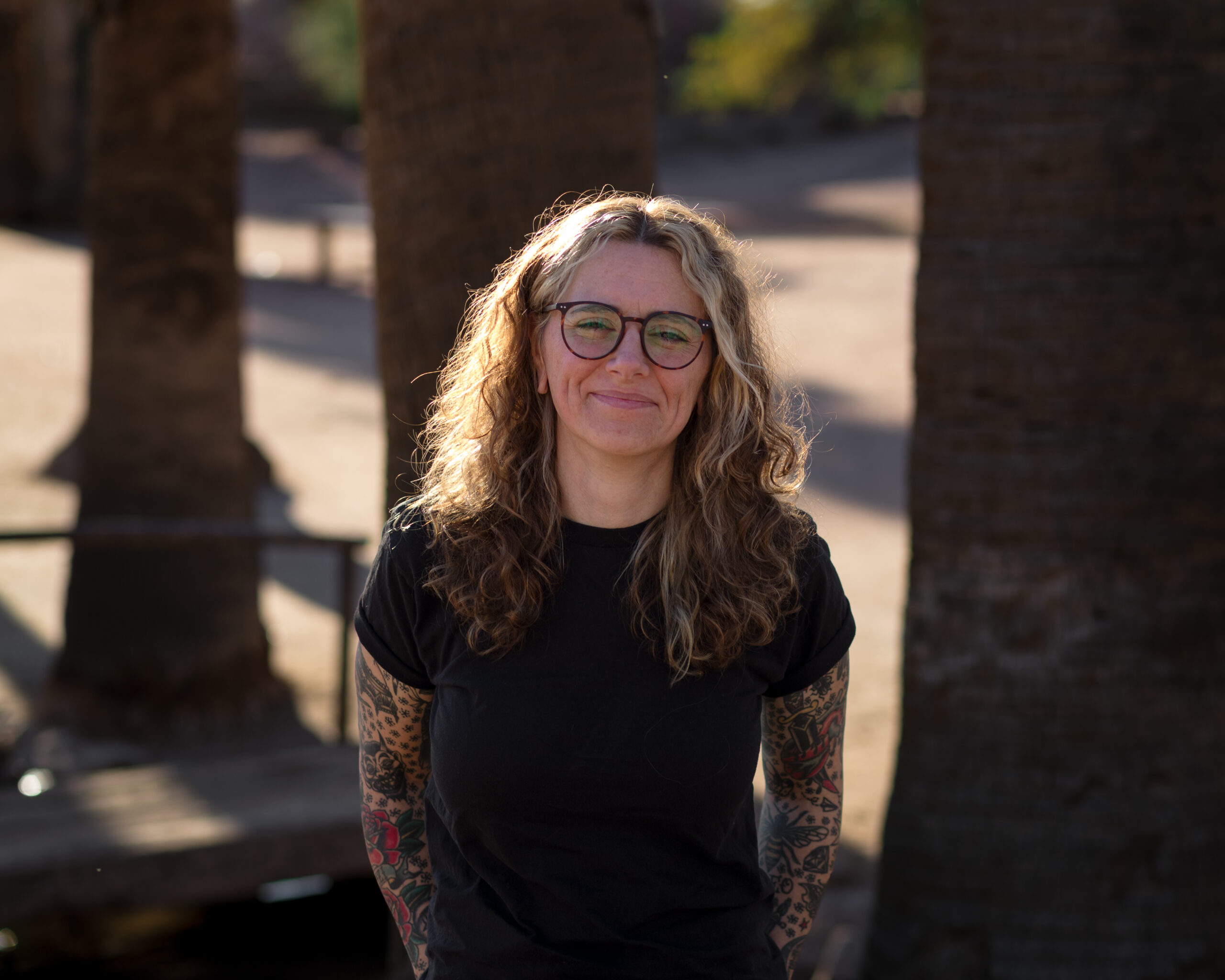 Compassionate therapist standing outdoors in soft sunlight, embodying a grounded and supportive presence for healing.